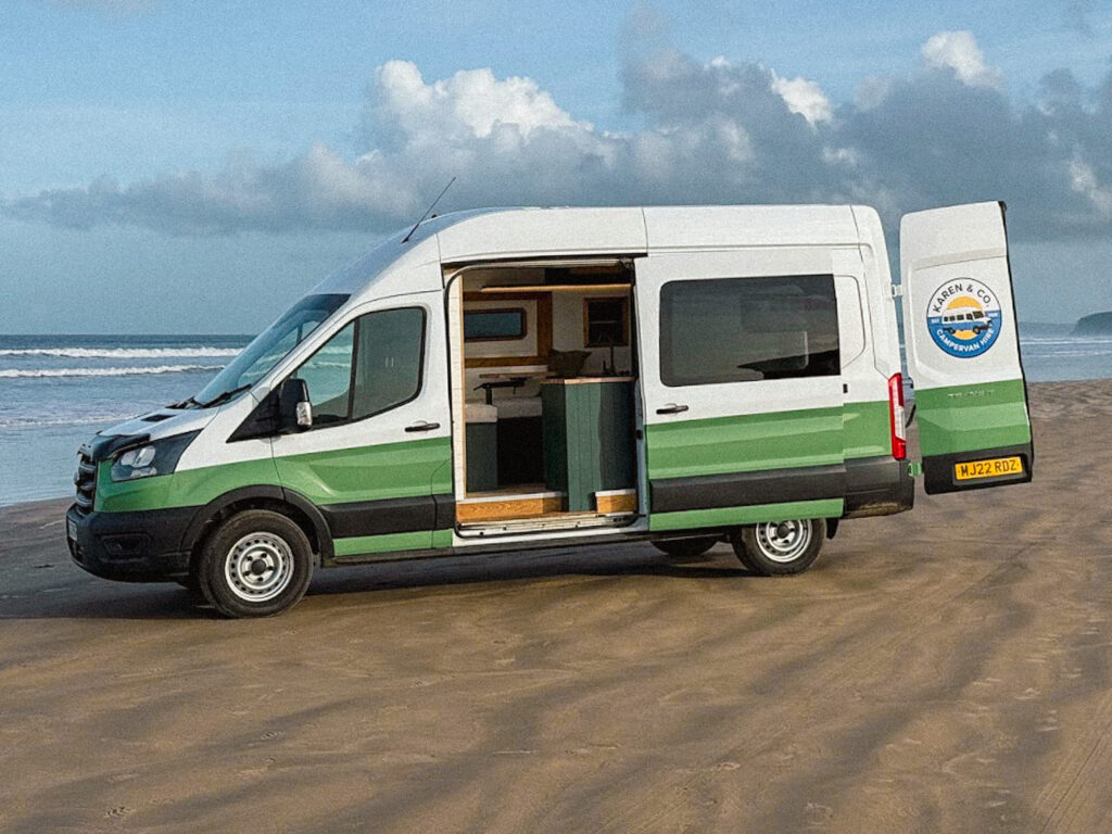 Campervan parked on sandy beach.