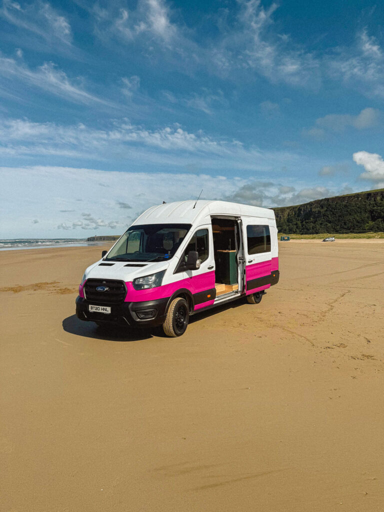 Campervan parked on sandy beach.