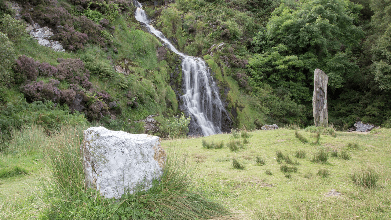 Assaranca Waterfall cascading down the hillside near Ardara, with stones in the foreground.