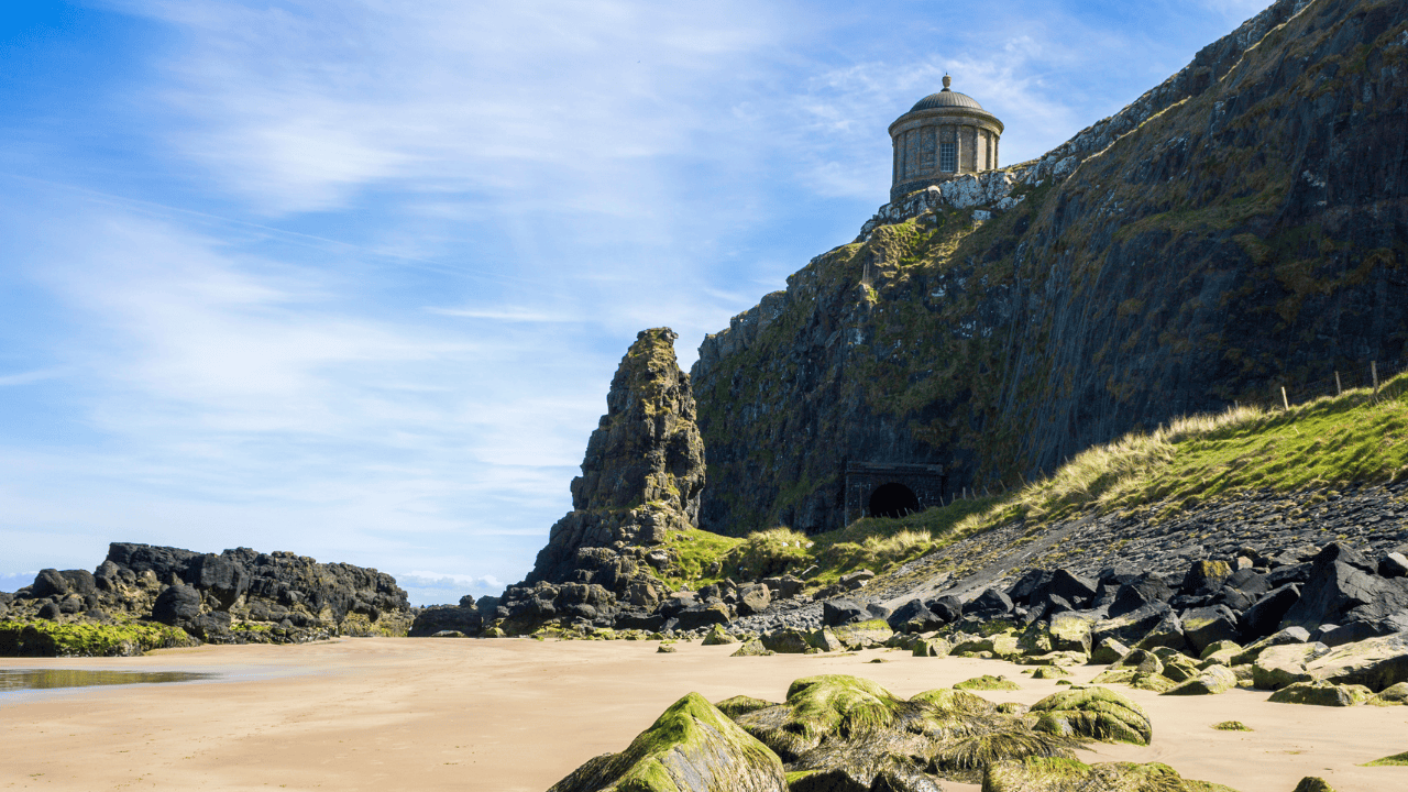Mussenden Temple on the cliffs above Downhill Beach, seen from the rocky shoreline.